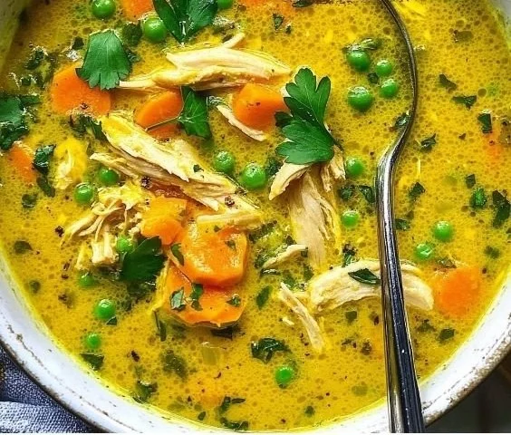 Bowl of anti-inflammatory turmeric chicken soup garnished with herbs.