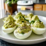 Avocado deviled eggs topped with paprika on a serving platter