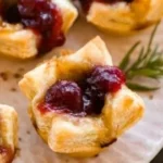Baked Cranberry Brie Bites on a serving platter with fresh herbs