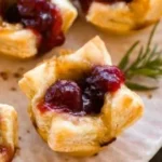 Baked Cranberry Brie Bites served on a platter with fresh herbs.