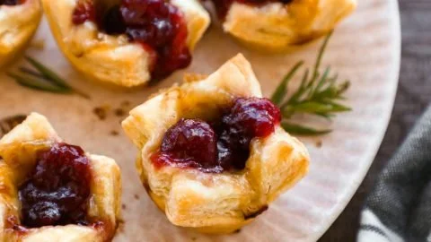 Baked Cranberry Brie Bites served on a platter with fresh herbs.