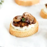Delicious Balsamic Mushroom Ricotta Crostini appetizer on a wooden serving board.