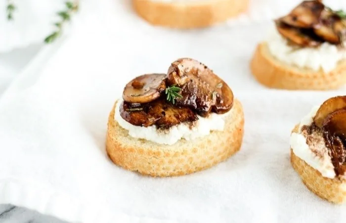 Delicious Balsamic Mushroom Ricotta Crostini appetizer on a wooden serving board.