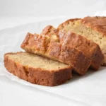 Loaf of freshly baked banana bread on a wooden cutting board