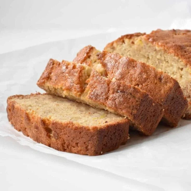 Loaf of freshly baked banana bread on a wooden cutting board