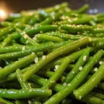Buttery garlic green beans served in a bowl, garnished with herbs.
