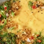 A bowl of creamy cauliflower potato soup topped with fresh herbs.