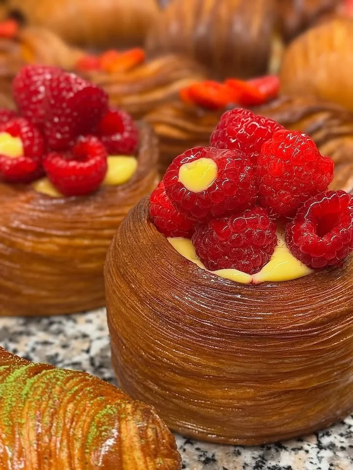 Freshly baked croissant on a wooden table with delicious pastries in the background