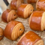 Golden brown croissant freshly baked, showcasing flaky layers and pastry perfection.