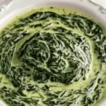 Delicious creamed spinach served in a bowl garnished with spices and cream.
