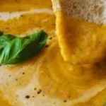 Creamy roasted veggie soup garnished with fresh herbs in a bowl