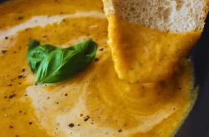 Creamy roasted veggie soup garnished with fresh herbs in a bowl