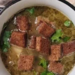 Bowl of traditional Czech Garlic Soup (Česnečka) garnished with herbs