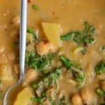 A bowl of high-protein chickpea soup with fresh herbs and spices.