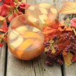 Crock pot filled with hot mulled apple cider sangria, garnished with spices and fruits.