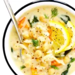 Bowl of Lemon Orzo Chickpea Soup garnished with fresh herbs and lemon slices