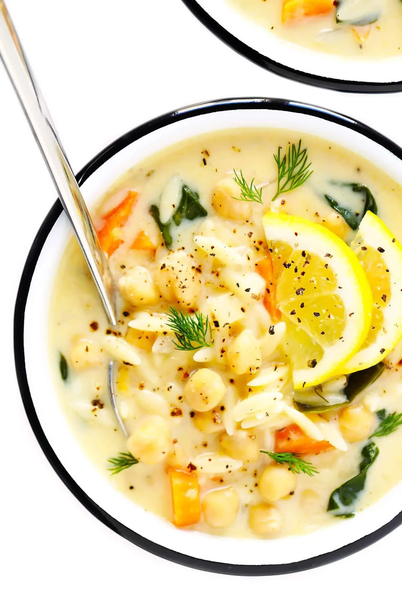 Bowl of Lemon Orzo Chickpea Soup garnished with fresh herbs and lemon slices