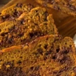 Slice of Pioneer Woman pumpkin chocolate chip bread on a wooden table