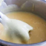 Bowl of creamy Potato Cauliflower Soup garnished with herbs.