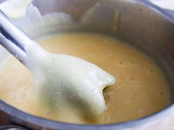 Bowl of creamy Potato Cauliflower Soup garnished with herbs.