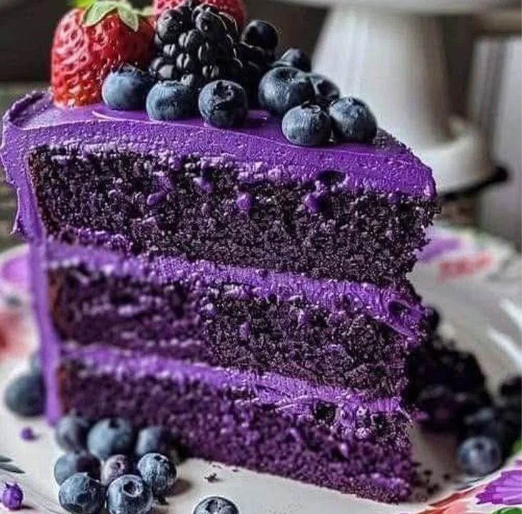 A slice of delicious purple velvet cake topped with cream cheese frosting.