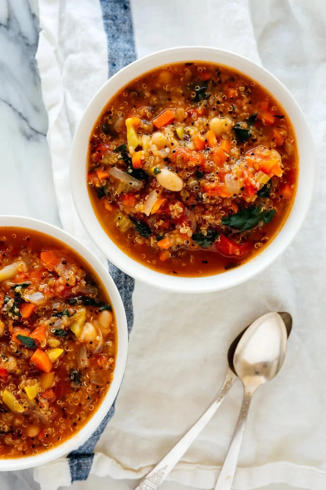 Bowl of quinoa vegetable soup filled with fresh vegetables and herbs