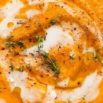 Bowl of creamy roasted butternut squash soup garnished with herbs.