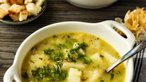 Delicious bowl of roasted garlic potato soup garnished with herbs