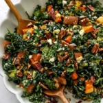 Roasted sweet potato kale salad drizzled with dressing and topped with nuts.