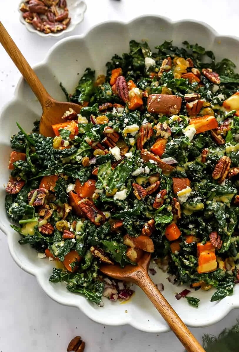 Roasted sweet potato kale salad drizzled with dressing and topped with nuts.