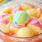 A colorful bowl of Sherbet Punch served with fruit slices and soda.