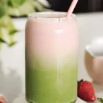 A vibrant Strawberry Matcha Latte topped with fresh strawberries and green matcha powder.