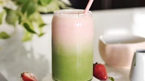 A vibrant Strawberry Matcha Latte topped with fresh strawberries and green matcha powder.