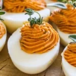 A platter of Thanksgiving deviled eggs garnished with herbs.