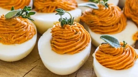 A platter of Thanksgiving deviled eggs garnished with herbs.