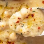 Delicious bowl of Vegan Garlic Chickpea Soup topped with herbs and spices.