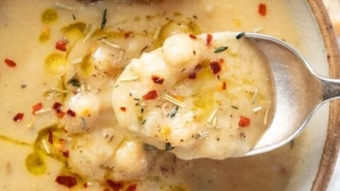 Delicious bowl of Vegan Garlic Chickpea Soup topped with herbs and spices.