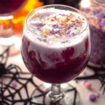 A colorful Witch's Brew Punch served in a spooky Halloween-themed glass.
