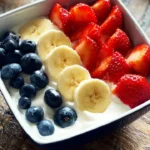 Colorful yogurt fruit bowl topped with fresh berries and granola.