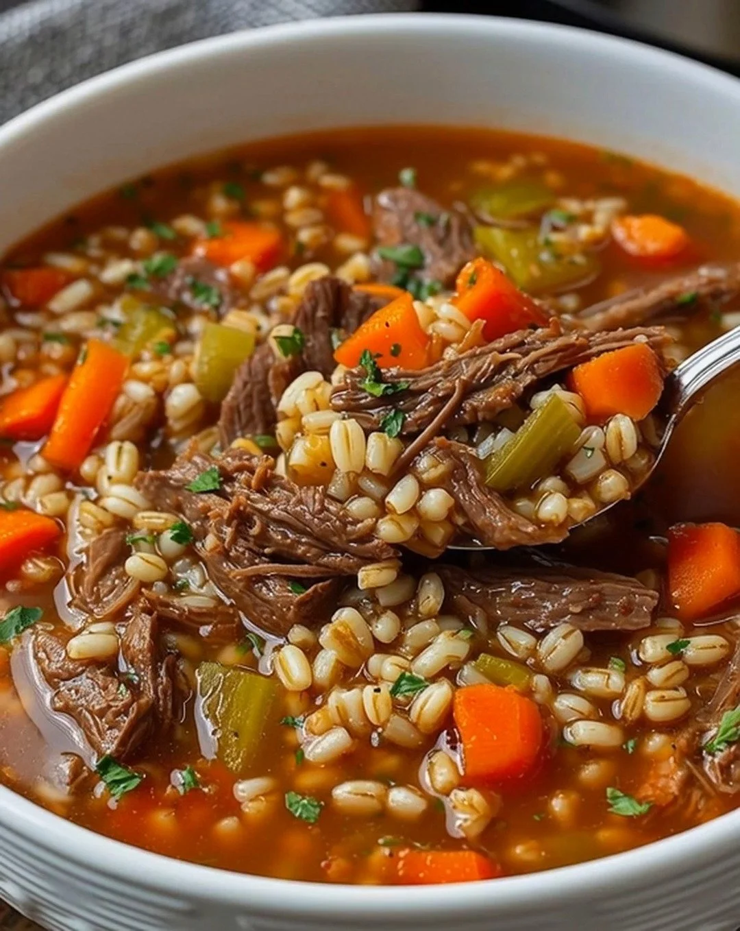 Bowl of delicious barley soup with vegetables and herbs