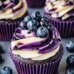 Blueberry chocolate cupcakes topped with cream frosting and fresh blueberries