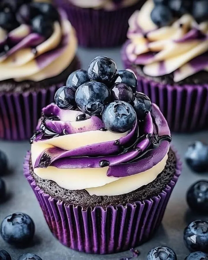 Blueberry chocolate cupcakes topped with cream frosting and fresh blueberries