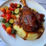 Delicious braised lamb shank served with creamy mashed potatoes and roasted vegetables