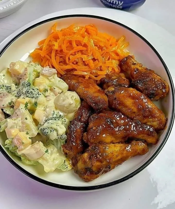 Delicious chicken wings served with potato salad, broccoli, and cauliflower