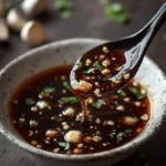 Bowl of Chinese Garlic Sauce with fresh garlic cloves and herbs