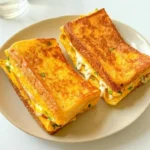Delicious egg toast sandwich topped with a sunny-side-up egg and herbs