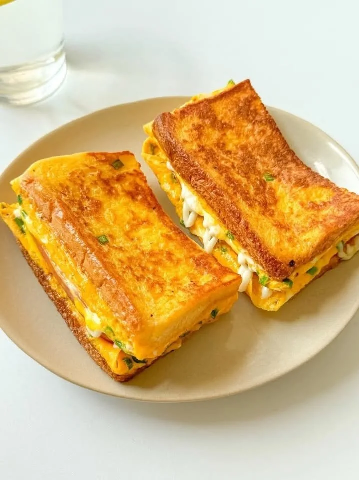 Delicious egg toast sandwich topped with a sunny-side-up egg and herbs