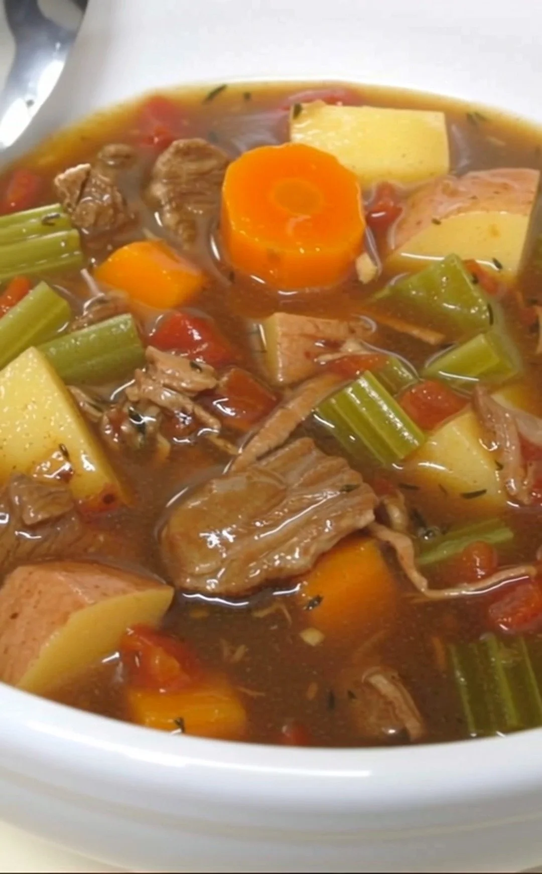A bowl of old-fashioned beef stew served with vegetables and herbs