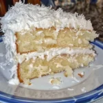 A beautifully frosted Southern Coconut Cake topped with toasted coconut flakes.