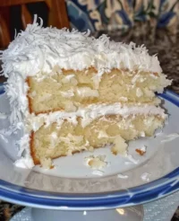 A beautifully frosted Southern Coconut Cake topped with toasted coconut flakes.